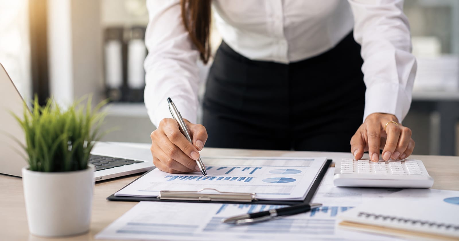Accountant reviewing financial statements and charts with calculator